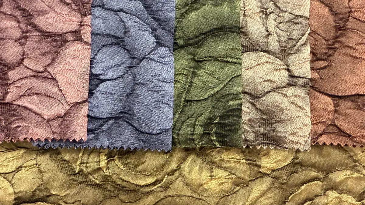 One crushed cloqué design shown in six colourways — dusty pink, blue, olive, sand, and terracotta, over a length of olive